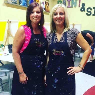 art | Scleroderma News | Amy and her sister, Christine, wear smocks and pose in front of easels in an art class they took together.