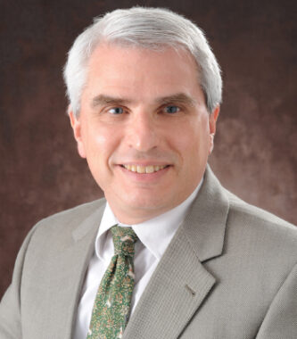 A professional headshot of Dr. Lee Shapiro, the chief medical officer and founder of the Steffens Scleroderma Foundation. He has gray-white hair and wears a gray suit jacket and patterned green tie.